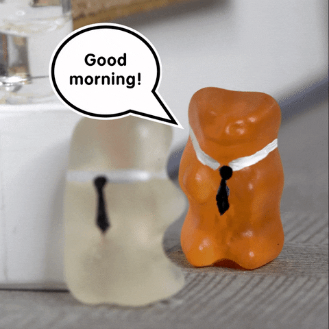 Stop motion gif. Two gummy bears with ties drawn on them, stand next to a watercooler their size, in a hallway. One movies slightly as it says, "Good morning!"