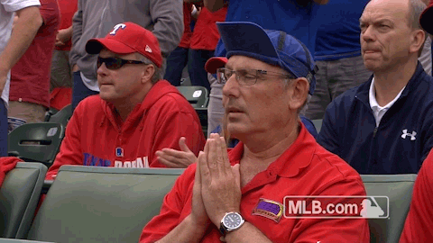 Sports gif. A Texas Rangers MLB fan presses his palms together in prayer from the stands.