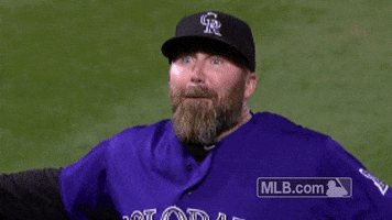 Sports gif. Jason Motte of the Colorado Rockies hand and glove collide as he excitedly shouts "boom" and looks up.