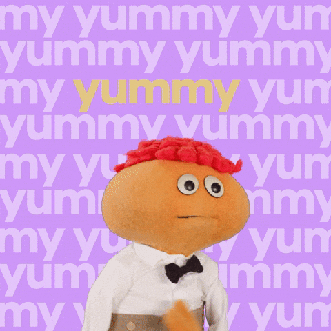 Video gif. Gerbert an orange puppet with orange hair, looks at us while bopping his round head. He opens his mouth to speak and we zoom in super close to his face. The background says, “Yummy.” over and over.