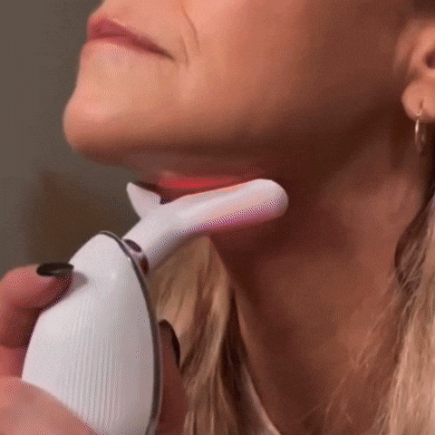 Woman using a neck massager with red light therapy on chin and neck area.