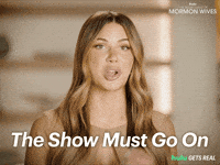 Sponsored gif. Reality star Demi Engemann from the reality show “The Secret Lives of Mormon Wives” smiles and makes circular gestures with both her hands. Text in front of her reads, “The show must go on.”