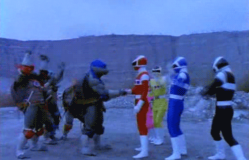 TV gif. In Power Rangers in Space, the Power Rangers meet the Teenage Mutant Ninja Turtles in a desolate landscape. The red Power Ranger, Jason Lee Scott, shakes Leonardo's hand while both crews jump and pump their fists in celebration.