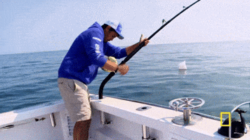 Reality TV gif. A man on Wicked Tuna is fishing and he's winding the fishing rod really quickly while the boat rocks. 
