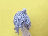 Video gif. A puppet with googly eyes and clacky teeth does a dramatic hair flip.