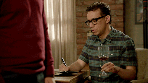 TV gif. Fred Armisen as Brandon in New Girl drops a glass of wine while writing, appearing startled as the glass falls to the floor.