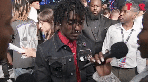 Celebrity gif. Lil Uzi Vert is being interviewed on the red carpet but instead of answering, he pouts his lips sassily and looks downwards while he does a slow shimmy.