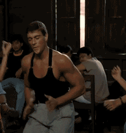 Movie gif. Jean Claude Van Damme as Kurt in Kickboxer gives a clap as he dances beside a woman in a bar.
