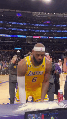 Sports gif. Lebron James of the Los Angeles Lakers walks tosses chalk in the air, creating a cloud of dust on the court before or after a game. He claps, coughs, then walks away.