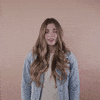 Reaction gif. A light-skinned woman with big eyes, shiny bronde hair, and cerebral palsy rolls her eyes with a toss of her head and brushes us off with a hand, saying, "Whatever!"