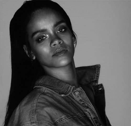Music video gif. From video for "FourFive Seconds," in black-and-white, Rihanna wears a denim jacket and looks over her shoulder at us, then rolls her eyes.