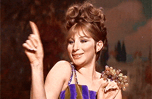 Movie gif. Barbra Streisand as Fanny Brice in Funny Girl points and smiles coyly.