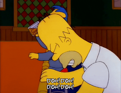 The Simpsons gif. A frustrated Homer Simpson repeatedly and deliberately knocks his head against the bar at Moe's Tavern. Behind him, a man with blue hair and glasses casually looks on while drinking a beer. Text, "D'oh! D'oh! D'oh! D'oh!"