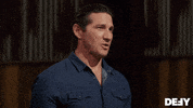 Reality TV gif. Wil Willis as host of Forged in Fire smiles and glances around as he says, "Welcome back to the Forge."