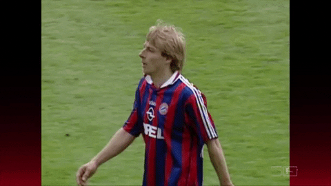 Sports gif. Jurgen Klinsmann of Bayern Munich is on the field and he high fives a teammate before moving into stretching his arms.