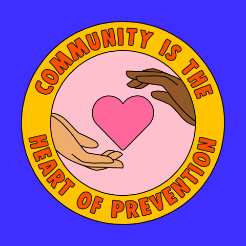 Digital art gif. Inside a circle with a yellow border is an animation of two cupped hands coming together to surround a pink heart. In the yellow border, text reads, "Community is the heart of prevention," all against a blue background.