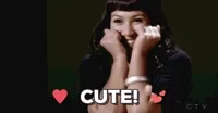 Video gif. A young woman smiles bashfully as she rests her hands adoringly to her face. Hearts rest to each side of white text, 