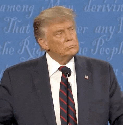 TV gif. Donald Trump stands in front of a mic at a presidential debate. He bites his cheek with an unamused look on his face, and then swats his hand to dismiss what he had just heard.