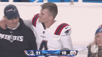 Sports gif. Bailey Zappe of the New England Patriots tosses his arm around a coach, looking happy and congratulatory, as they walk next to each other.