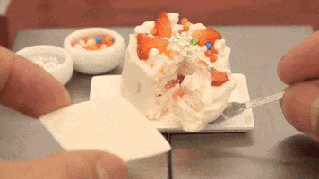 Video gif. A pair of hands cuts a slice of a tiny strawberry cake, and we're talking real tiny, like doll-sized cake.