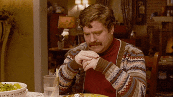 Movie gif. With a moustache and a complicated cardigan, Zach Galifianakis holds his hands together and stares pensively at his dinner plate. He turns to us and sadly asks: Text, "Why?"