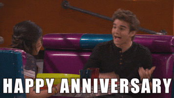 TV gif. Jack Griffo as Max on The Thundermans sits in a diner booth across from a young woman as he spreads his arms and says, "Happy anniversary."
