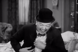 Movie gif. Stan Laurel in Way Out West is laughing hysterically. He fixes his coat and tries to catch his breath, but can’t stop laughing.