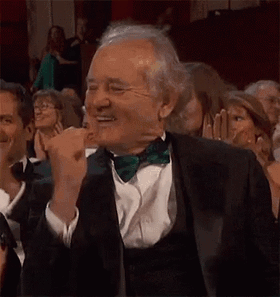 Celebrity gif. Bill Murray gives a celebratory gesture as he stands in applause. 
