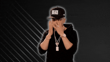 Video gif. Singer Yandel does a face palm, burying his head in his hands. 