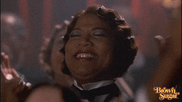 Movie gif. Queen Latifah as Mama in Chicago shouts joyfully with her eyes closed and her fist up, amid an applauding crowd.