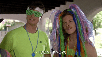 TV gif. Blake Anderson and Anders Holm on Workaholics wearing colorful, silly outfits. Blake, with a headpiece made of multicolored hair extensions and plastic tubes, cocks his head to the side and says, “I don’t know.” Anders looks on with an awkward smile.