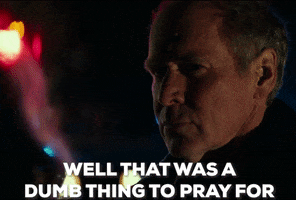 Movie gif. Will Patton as Deputy Hawkins in Halloween stands in the dark, with police lights in the background and says, “Well that was a dumb thing to pray for.”