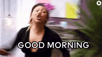 Reality TV gif. Scene from Bad Girls Club. A Woman walks into a room, throwing her arms around, and yelling at the top of her lungs, “Good morning!”