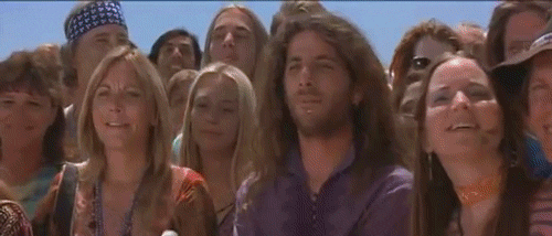 An animated gif clip from the movie Mars Attacks. In the desert, there is a large flying saucer landed with a martian standing in front of it. Among the large group of people there to witness the event is a group of hippies, one of whom releases a dove as a symbol of peace. The martian shoots the dove.