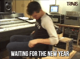Celebrity gif. Neil from the band Travis spins in an office chair in a recording studio. Text, "waiting for the new year."