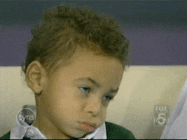 Video gif. A little boy is not amused as he lets his head hang down and shakes it solemnly.
