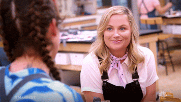 Reality TV gif. Amy Poehler in Making It. She leans on a table and listens intently to a contestant's plans before straightening up in interest, raising her eyebrows and dropping her jaw, intrigued with what she's heard. 